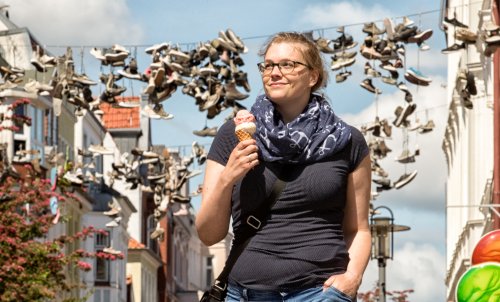 Studentin Marlen schlendert mit Eis durch bekannte Flensburger Straße, in der Schuhe über Leinen baumeln.