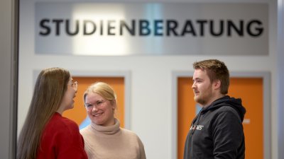 Drei Studierende unterhalten sich vor dem Büro der Studienberatung