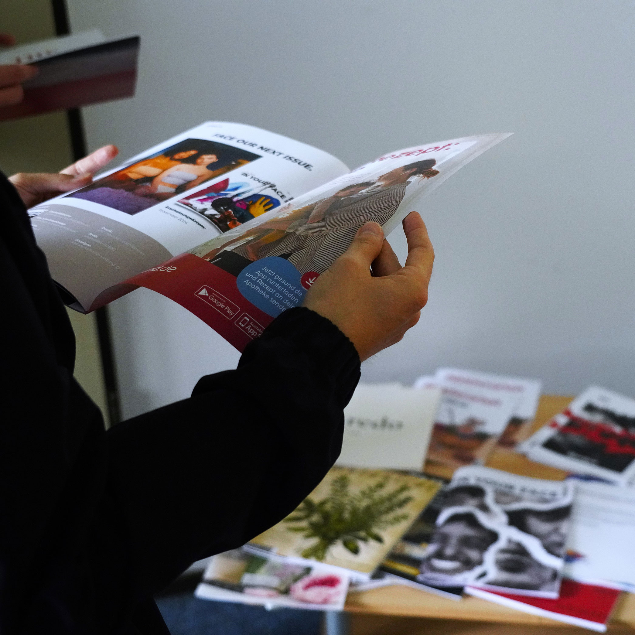 Zwei Hände halten ein geöffnetes Magazin, auf dem Tisch im Hintergrund liegen weitere Magazine.