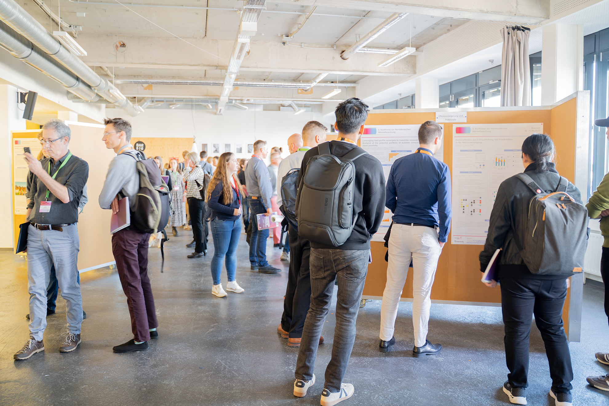Posterausstellung auf einer Konferenz: Mehrere Menschen stehen in Gruppen und einzeln vor verschiedenen Postern.