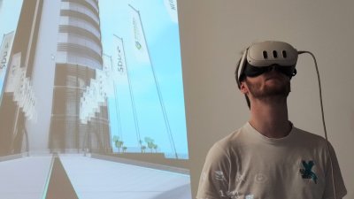 Ein Mann mit VR ist vor einem Bildschimr zu sehen