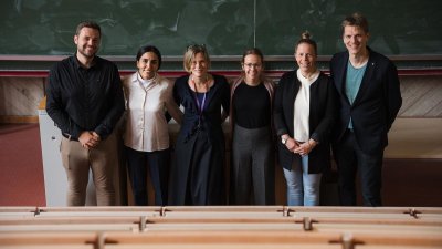 Man sieht sechs Personen im Hörsaal stehen