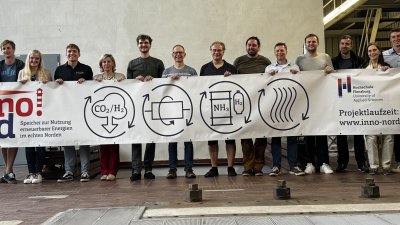 zirka 20 Menschen stehen in einer Reihe und halten ein Plakat des Projektes Inno-Nord
