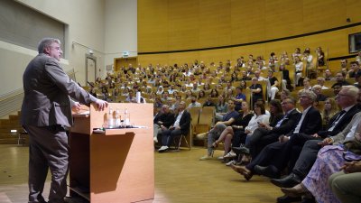 Ein Mann am Rednerpult vor einem großen Publikum