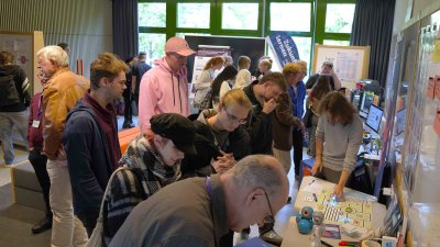 Viele Menschen in einem Raum beschauen Exponate