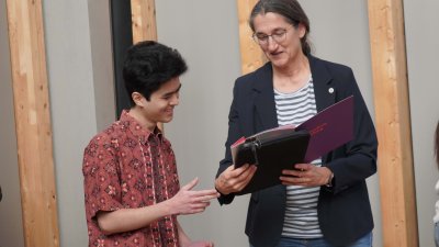 Eine Frau übergibt einem jungen mann eine Urkunde