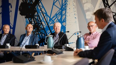 Vier Männer schauen auf einen Mann, der nur verschwommen im Anschnitt zu sehen ist