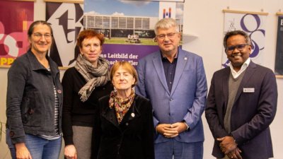 Fünf Menschen stehen in einer Reihe und schauen in die Kamera