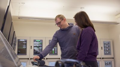 Zwei Menschen stehen am Schiffsmaschinensimulator