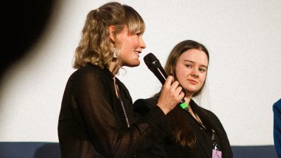 Zwei Frauen, eine spricht in ein Mikro, die andre schaut sie an