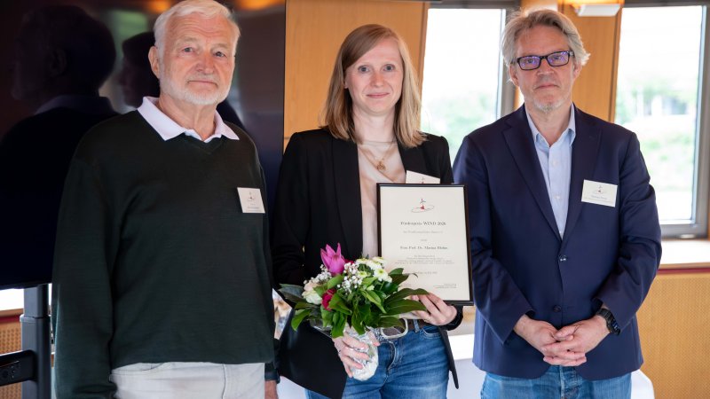 Eine Frau steht mit Blumenstrauß zwischen zwei Männern