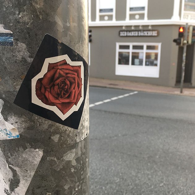 Ein Aufkleber auf einem Mast (vielleicht eine Ampel).