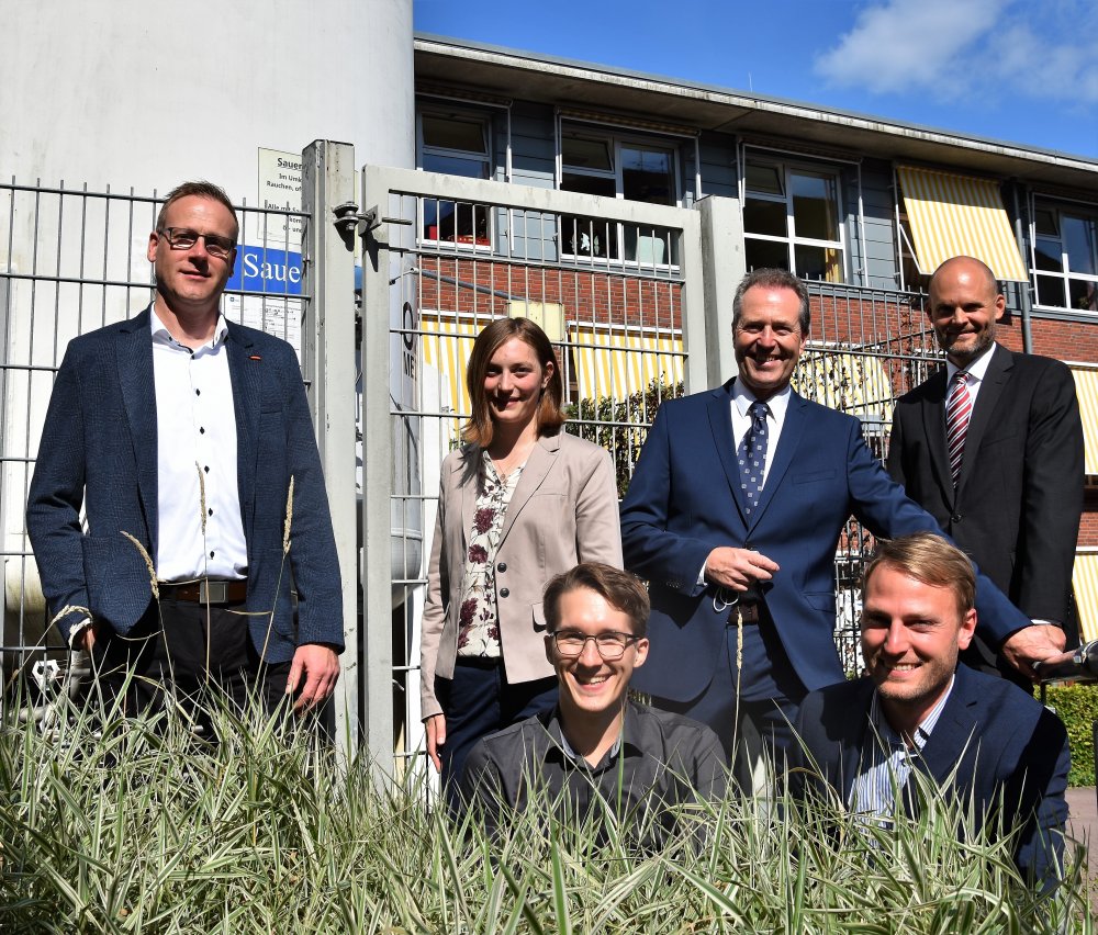 Das Projektteam: Thomas Flemig (Technischer Leiter, Malteser), Samanta Weber (wiss. Mitarbeiterin, Hochschule Flensburg), Jürgen Freitag (Leiter Immobilien, Bau und Technik, Diako-Krankenhaus) und Prof. Dirk Volta (Projekteiter, Hochschule Flensburg) (v.l.n.r. stehend) sowie (vorne sitzend von links) Ruben Harten und André Lindemann (beide Projektingenieure, Hochschule Flensburg). Links im Hintergrund: Der Sauerstofftank für das Diako-Krankenhaus.