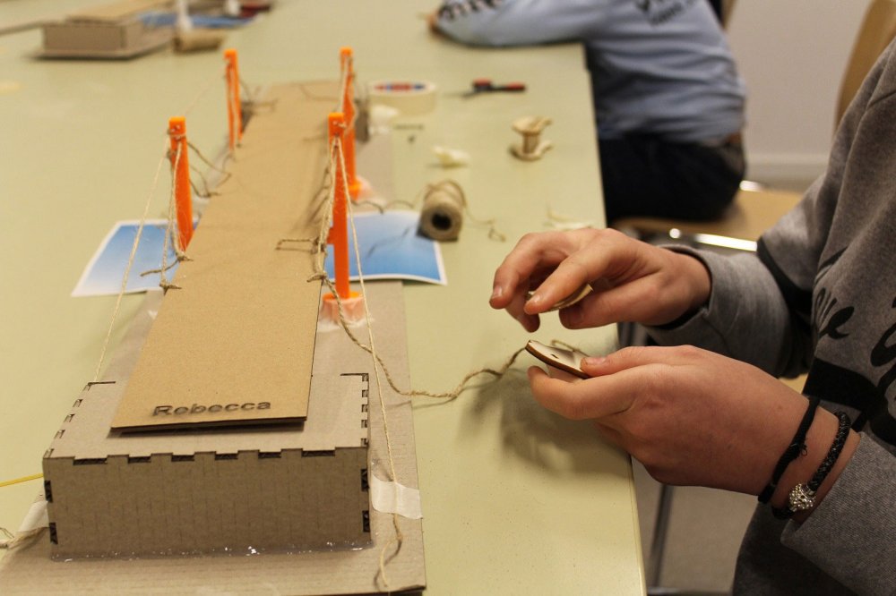 Brücke auf einem Tisch und Händde, die daran arbeiten.