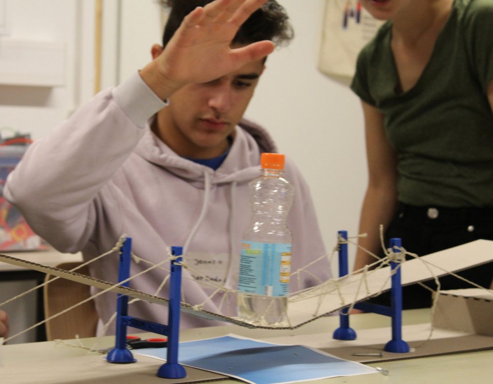 Junger Mann platziert Wasserflasche auf Brücke.