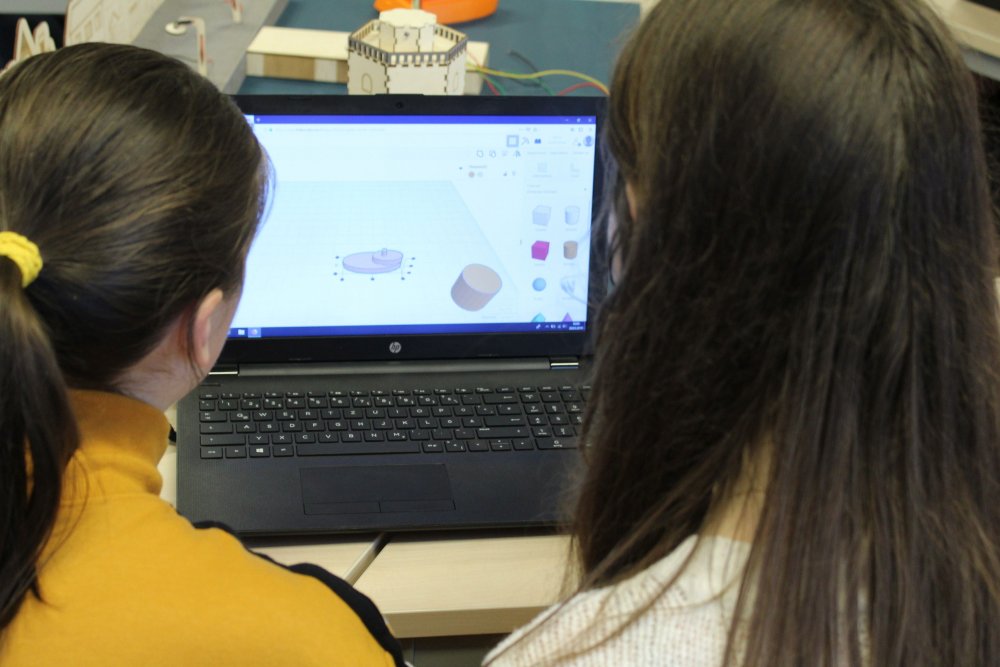 Zwei junge Frauen blicken auf einen Laptopbildschirm.