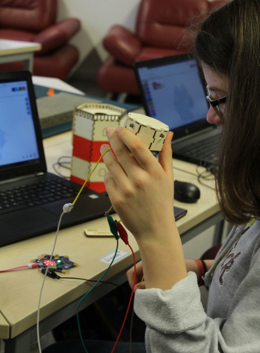 Junge Frau arbeitet an ihrem Projekt; Kabel und ein Laptop auf einem Tisch.