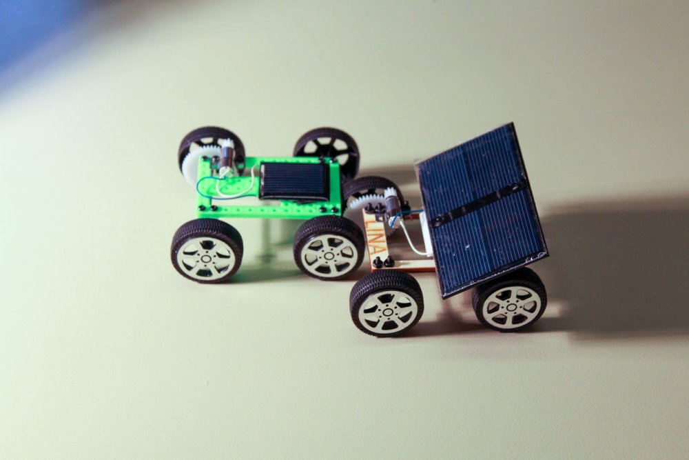 Zwei Solarautos auf hellem Untergrund, eines mit Solarzellen.