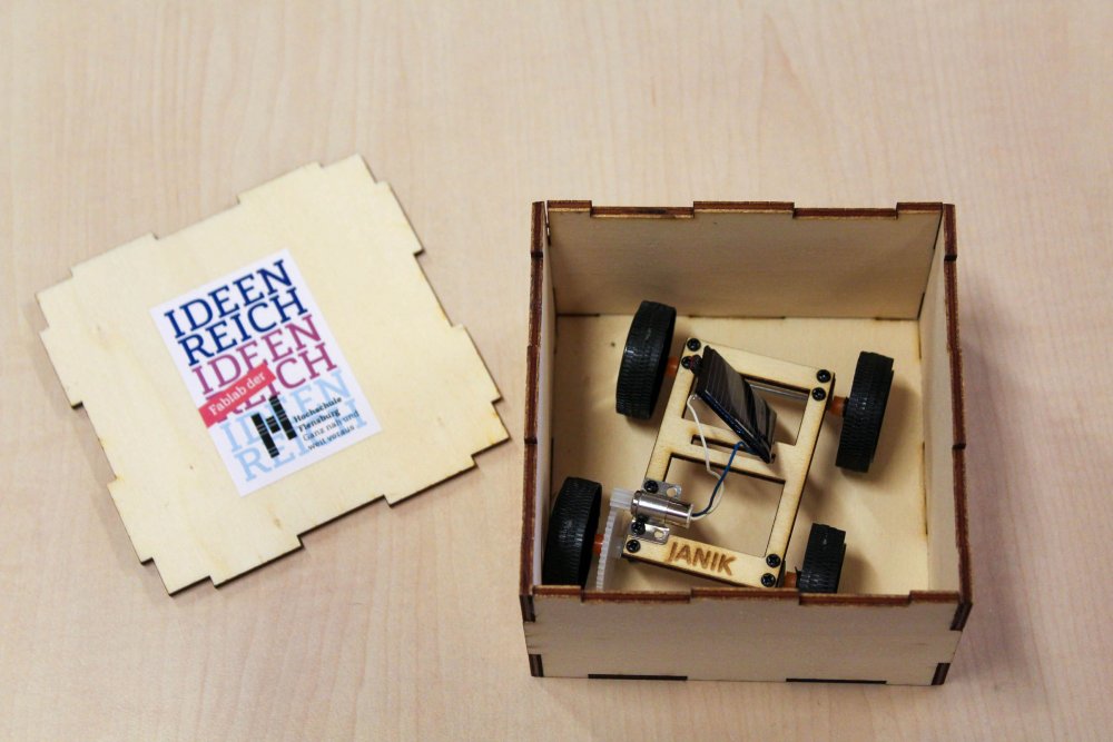 Fertiges Solarauto in selbstgemachter Box, daneben der Deckel mit IDEENREICH-Logo.