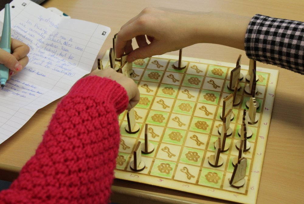 Selbstgemachtes Spielbrett, Hände die spielen und Notizen machen.