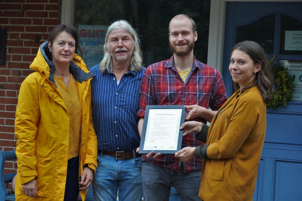 Rebekka Küchler, wissenschaftliche Mitarbeiterin der Hochschule Flensburg, überreicht Familie Lorenzen die Teilnahmebescheinigung. 