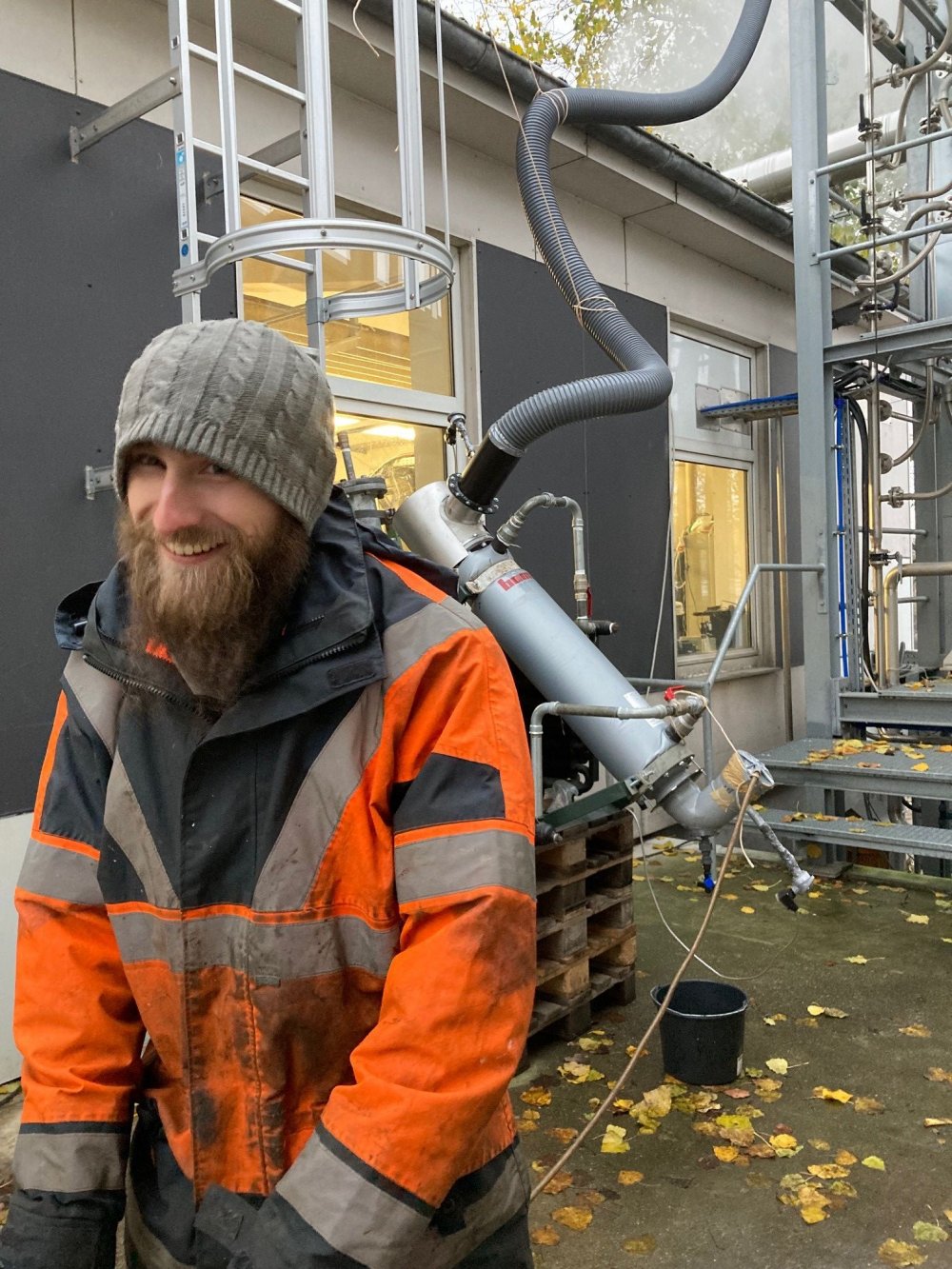 Junger Mann steht draußen vor den Rohren der Scrubberanlage.