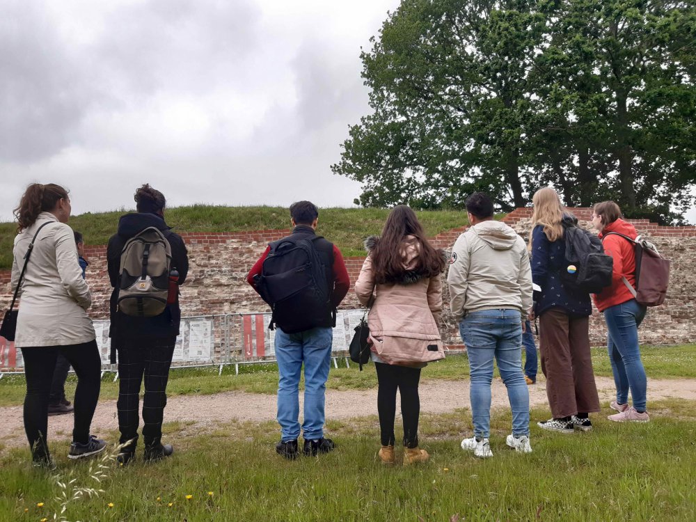 Gruppe von Menschen schaut auf einen Wall. Sie sind von hinten zu sehen und tragen recht warme Kleidung.