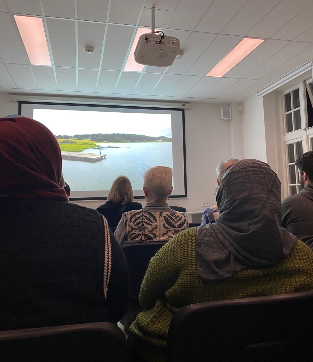 Menschen schauen auf eine Leinwand. Sie sind von hinten zu sehen.
