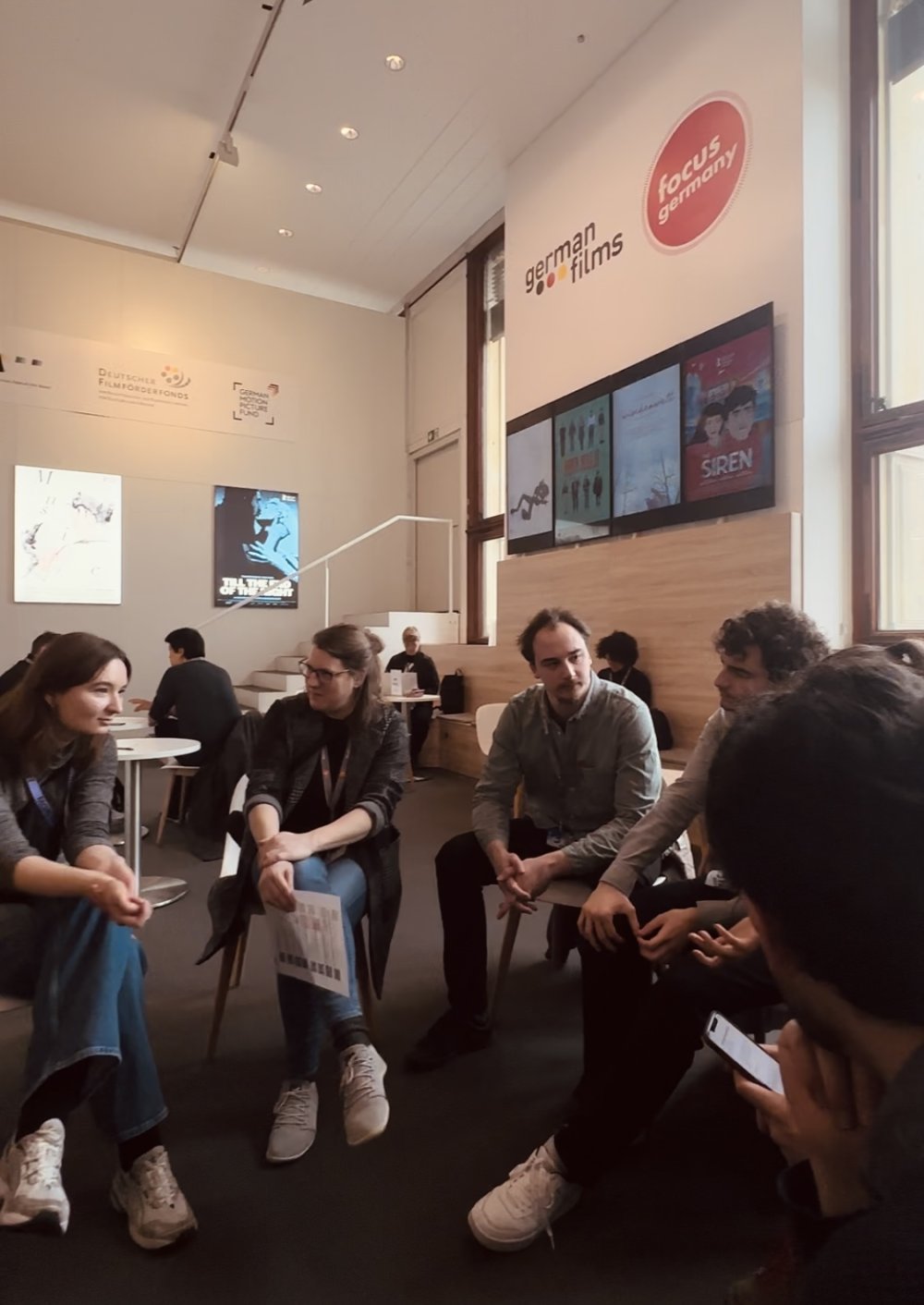 Gruppe von Menschen sitzen im Kreis, sie sind ins Gespräch vertieft.