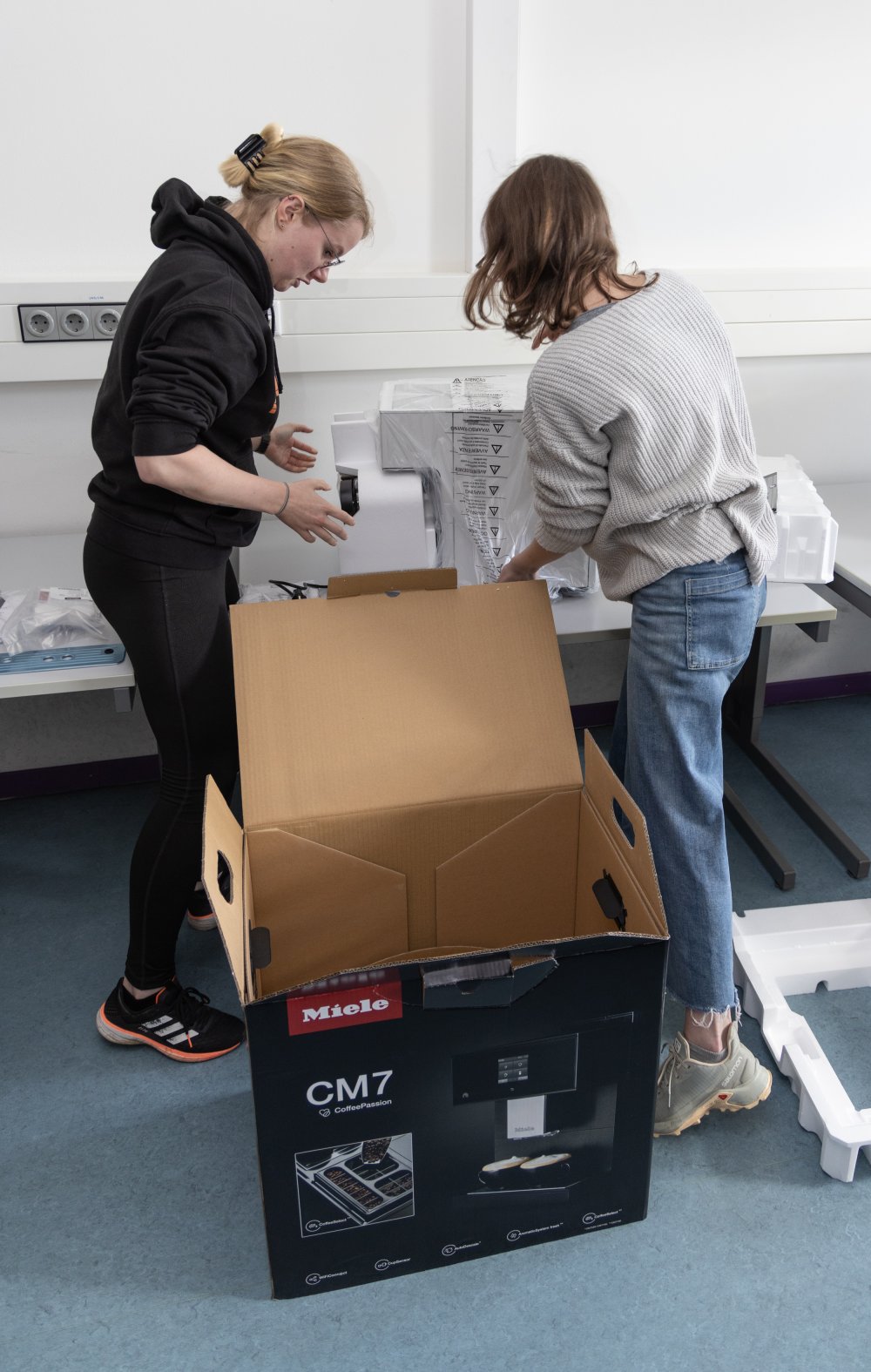 Die Studierenden packen die Kaffeevollautomaten aus.