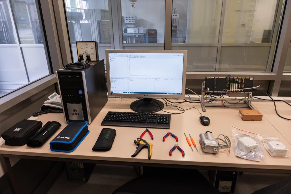 Ein PC-Arbeitsplatz mit angeschaltetem Monitor, davor sind verschiedene Werkzeuge ausgebreitet.