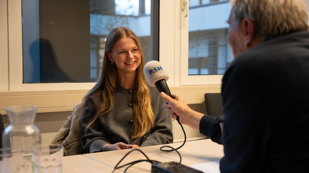 Emma spricht in ein Mikrofon, das ihr hingehalten wird. 