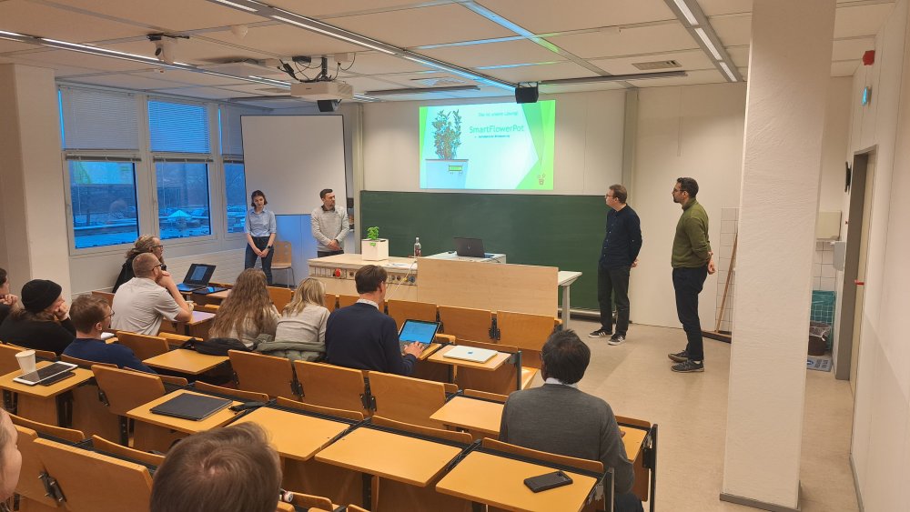 In einem Seminarraum steht vorne eine Gruppe von Studierenden und hält eine Präsentation.