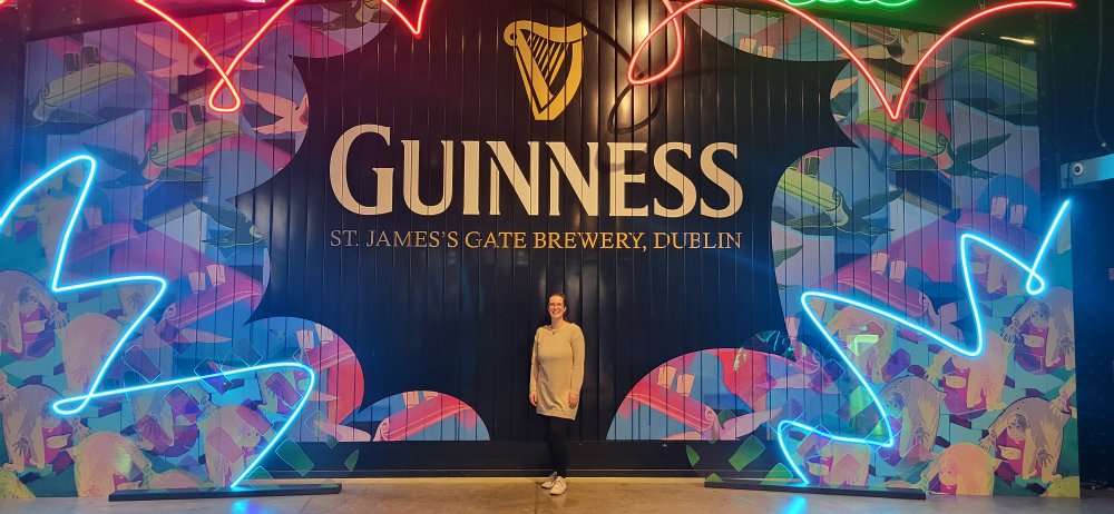 Man sieht eine Frau vor einem Schild auf dem Guiness steht