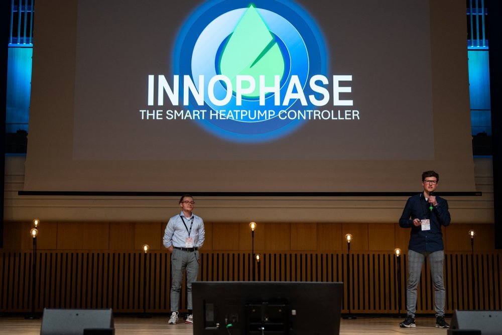 Auf einer großen Bühne stehen zwei junge Männer und halten einen Vortrag.