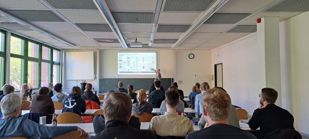 In einem Seminarraum sitzen Studierende, vorne steht ein Mann und hält einen Vortrag, seine Präsentationsfolie trägt den Titel &quot;Die Rolle von Wasser in der Brauerei&quot;.