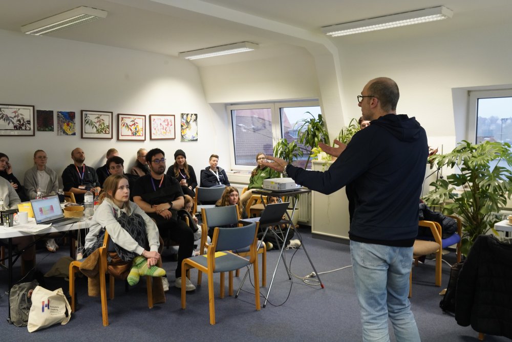 Ein Mann steht vor Studierenden und erklärt