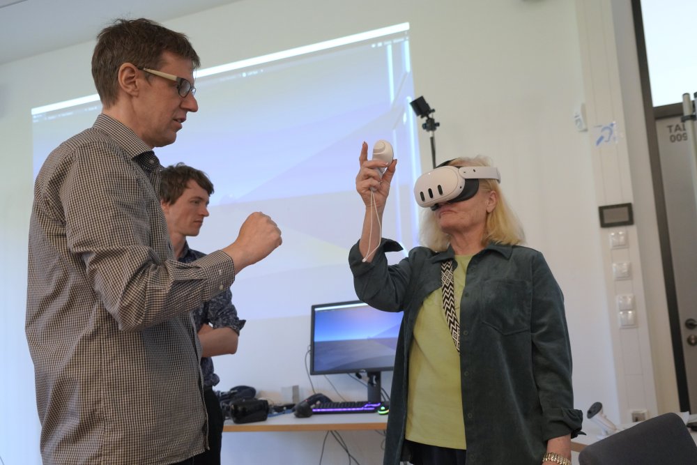 Eine Frau trägt eine VR Brille, ein Mann schaut zu
