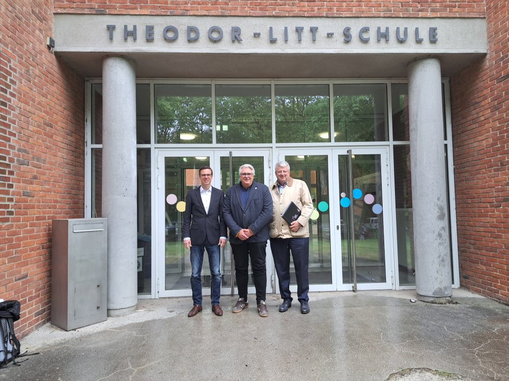 Drei Männer vpr der Tür einer Schule