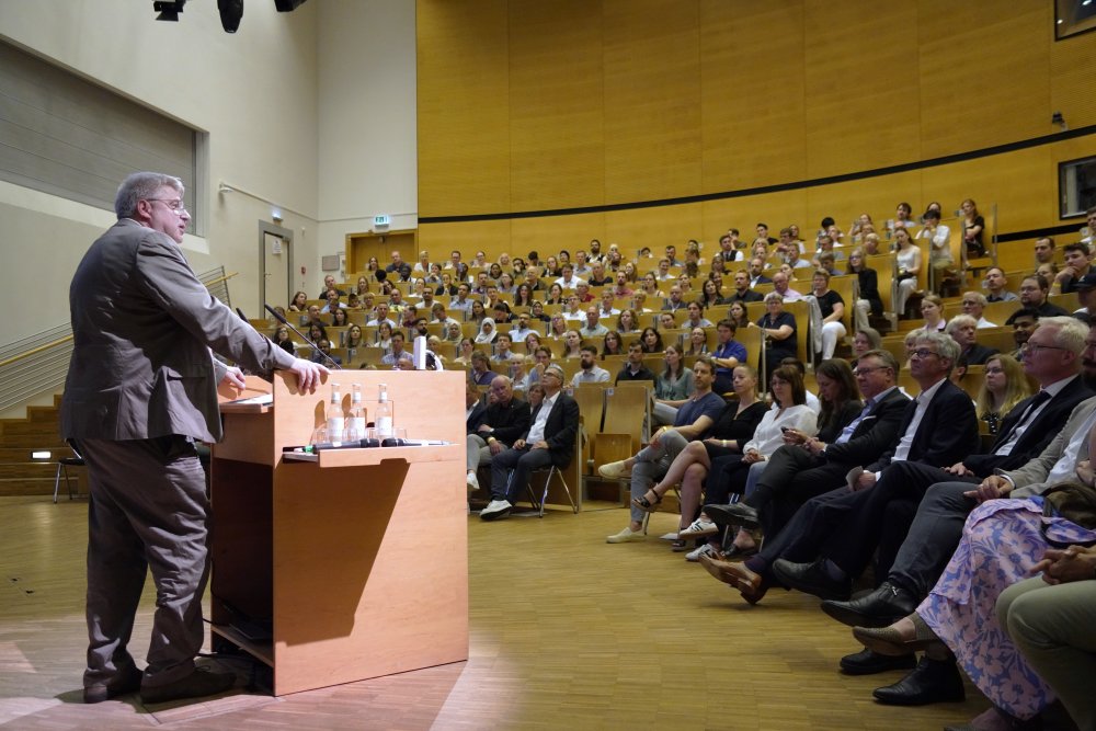 Ein Mann am Rednerpult vor einem großen Publikum