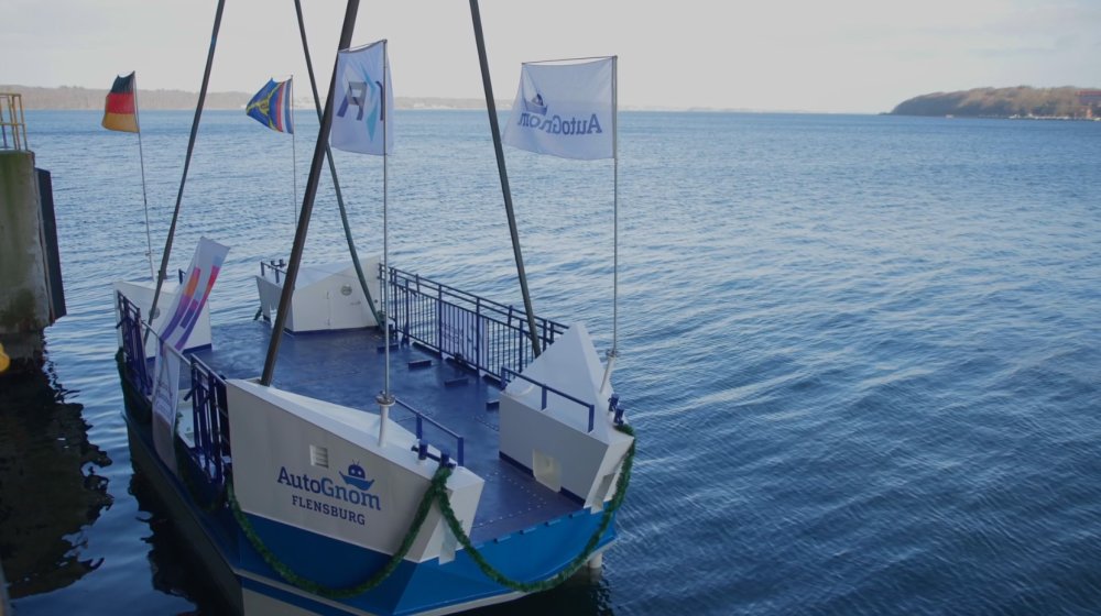 Die Fähre auf dem Wasser, sie ist noch an Seilen befestigt und mit Fahnen dekoriert.
