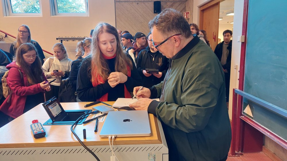 Ein mann gibt Autogramm, viele MEnschen warten.