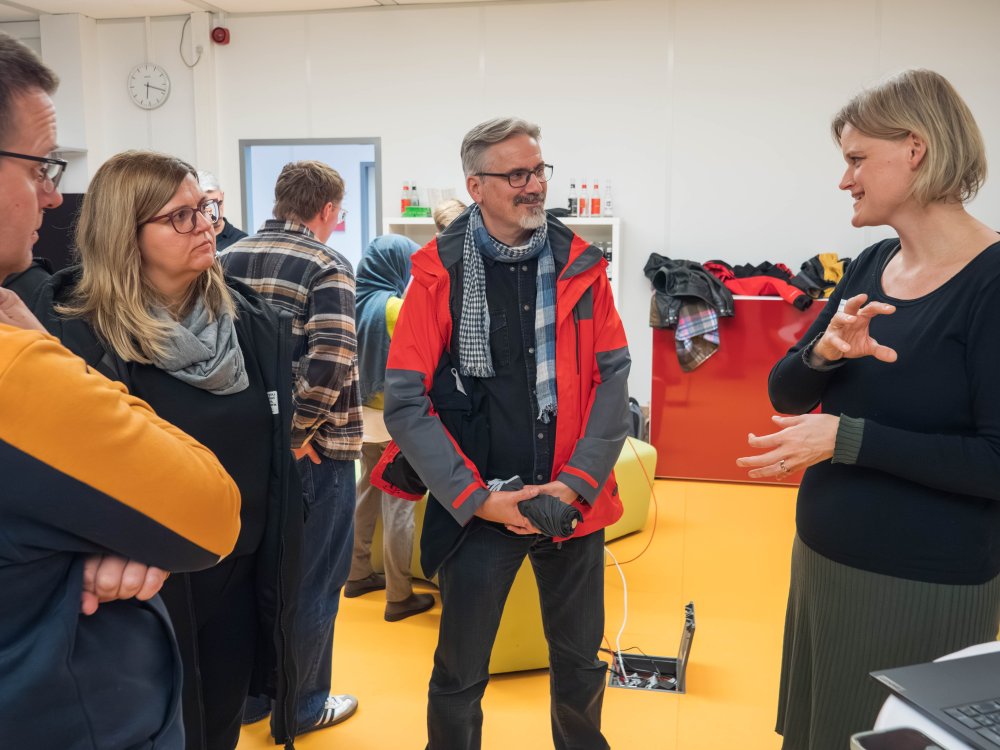 Viele MEnschen in einem Raum, die sich unterhalten. 