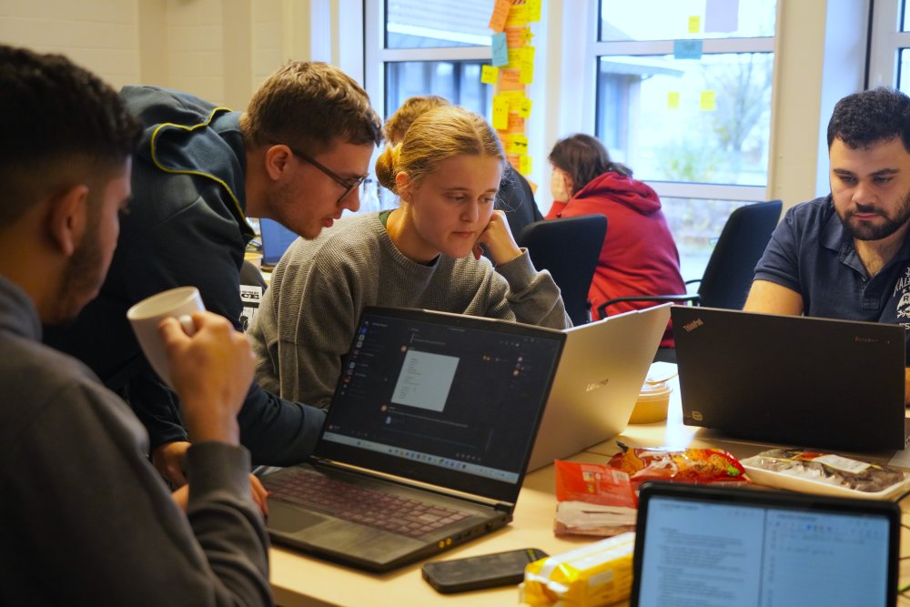 Viele Menschen stehen zusammen und schauen auf einen Laptop