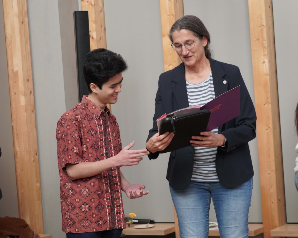 Eine Frau übergibt einem jungen mann eine Urkunde