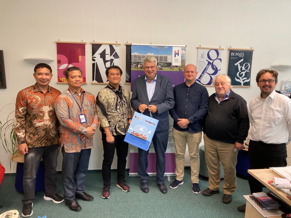 sieben Männer stehen im Halbreis und schauen in die Kamera