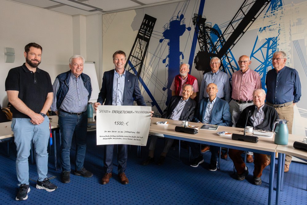 Viele Menschen, einer hält einen großen Scheck in der Hand