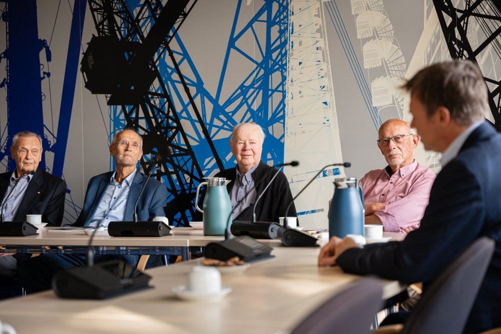 Vier Männer schauen auf einen Mann, der nur verschwommen im Anschnitt zu sehen ist