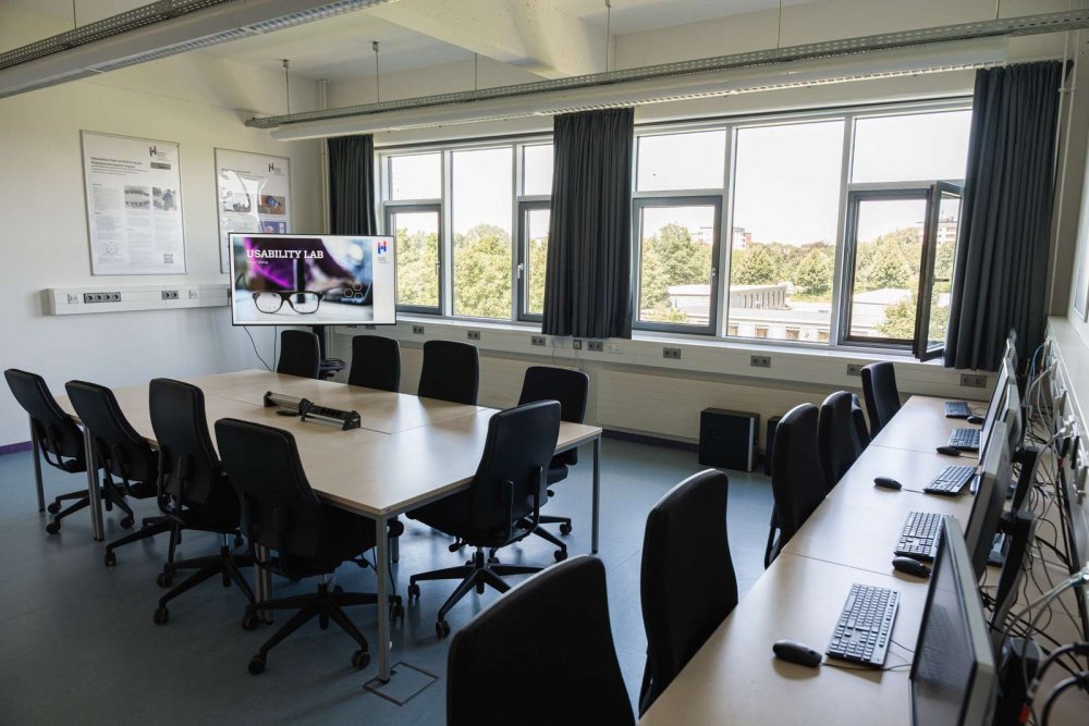 Laborraum mit Tischen und PC-Arbeitsplätzen, auf einem großen Monitor steht &quot;Usability Lab&quot;.