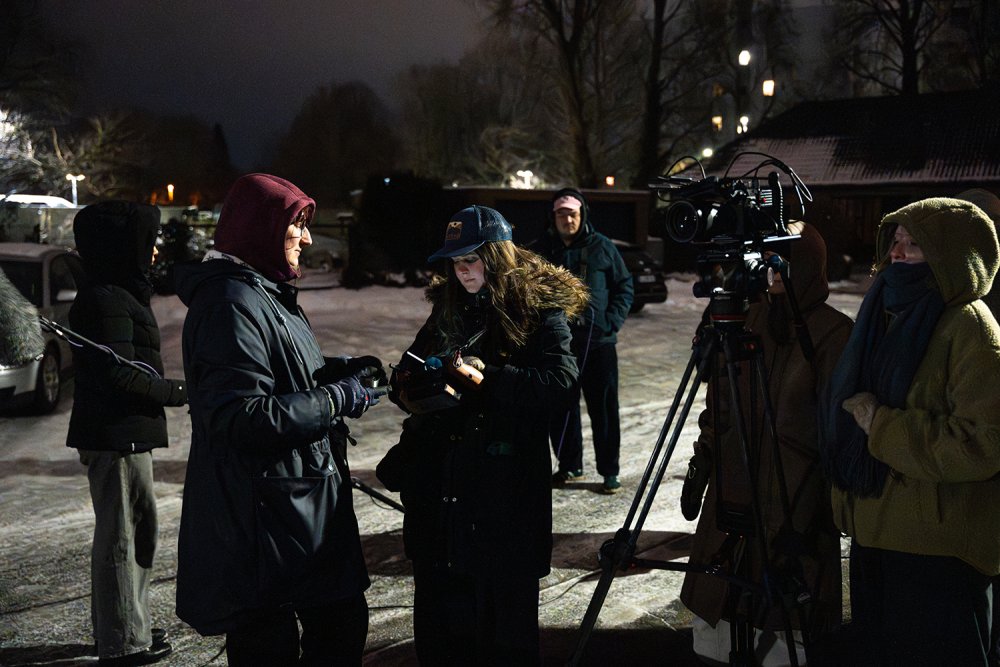 Eine Gruppe von Studierenden bei einem Filmdreh auf einer winterlichen Straße berät sich.
